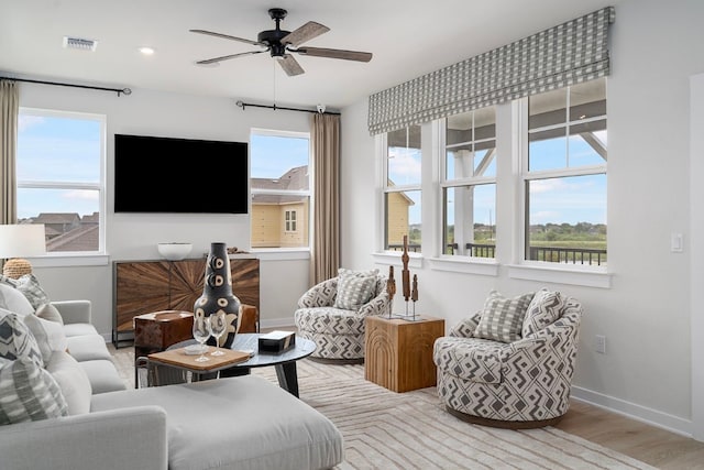 living room featuring ceiling fan, light hardwood / wood-style floors, and a healthy amount of sunlight