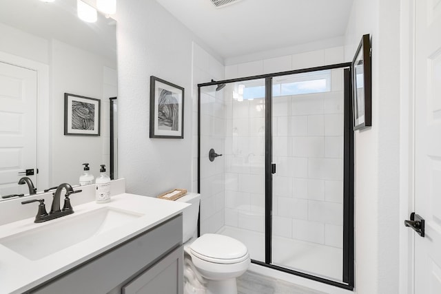 bathroom with vanity, toilet, and a shower with door