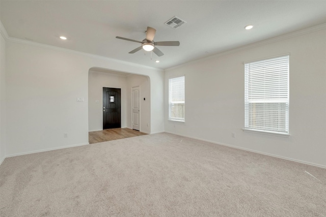 empty room with ceiling fan, light colored carpet, and ornamental molding