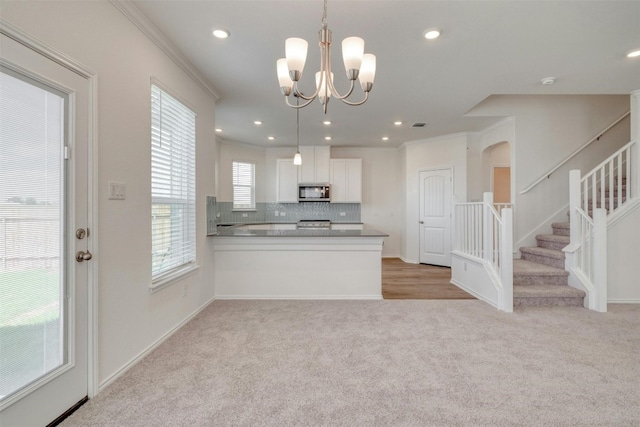 kitchen featuring white cabinetry, tasteful backsplash, kitchen peninsula, crown molding, and decorative light fixtures