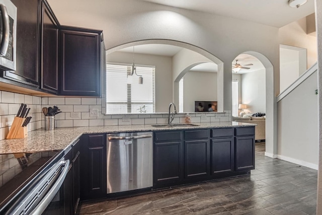 kitchen featuring light stone counters, sink, ceiling fan, dark hardwood / wood-style floors, and appliances with stainless steel finishes