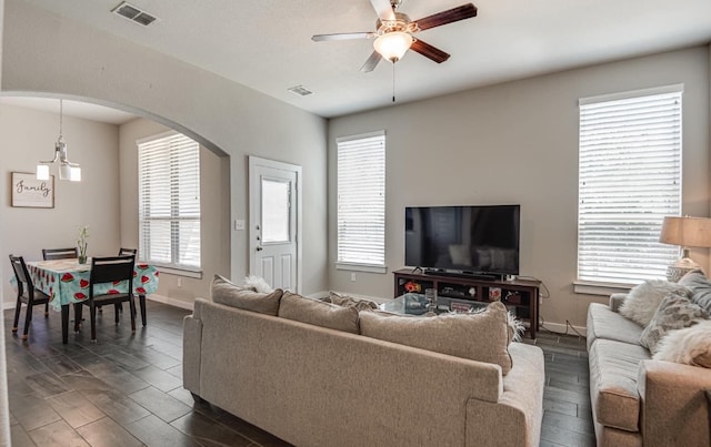 living room with a healthy amount of sunlight, ceiling fan, and dark wood-type flooring