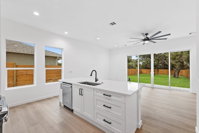 kitchen with white cabinetry, an island with sink, sink, ceiling fan, and light hardwood / wood-style floors