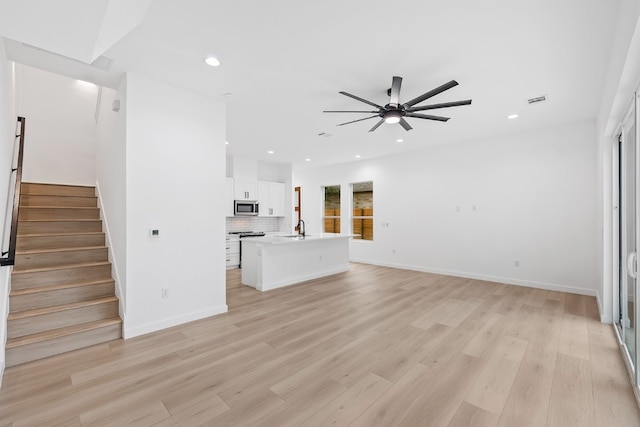 unfurnished living room featuring plenty of natural light, light hardwood / wood-style flooring, sink, and ceiling fan