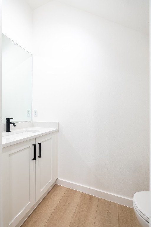 bathroom with hardwood / wood-style floors, toilet, and vanity