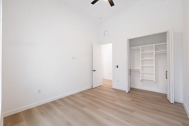 unfurnished bedroom with light wood-type flooring, a closet, ceiling fan, and high vaulted ceiling