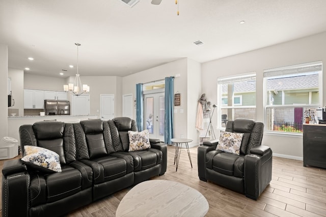 living room with ceiling fan with notable chandelier and light hardwood / wood-style floors