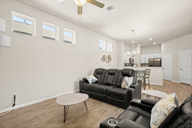 living room with light hardwood / wood-style floors and ceiling fan with notable chandelier