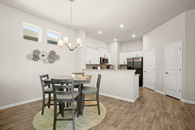 dining area featuring sink, light hardwood / wood-style floors, and an inviting chandelier