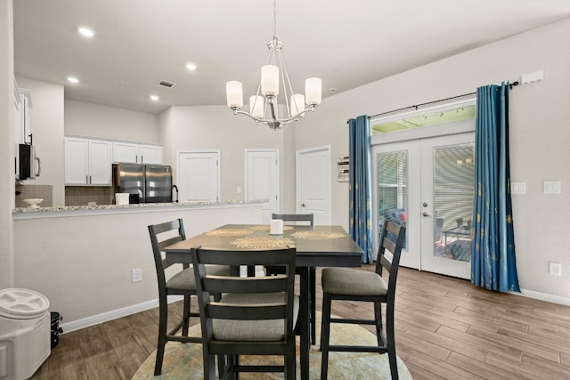 dining space featuring sink, french doors, light hardwood / wood-style floors, and an inviting chandelier