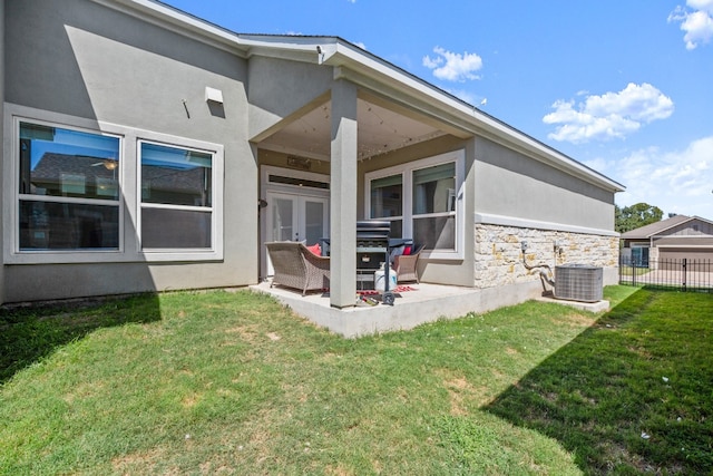 rear view of house with a lawn, central AC, and french doors