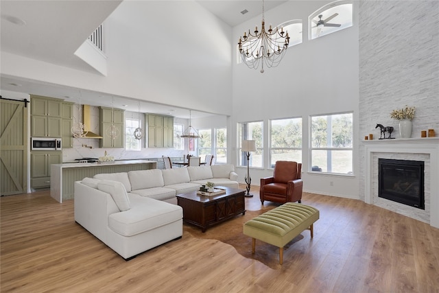 living room featuring a healthy amount of sunlight, a stone fireplace, and a towering ceiling