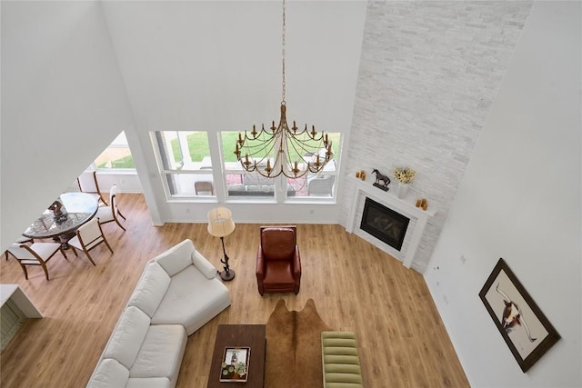 living room with a large fireplace, wood-type flooring, and an inviting chandelier