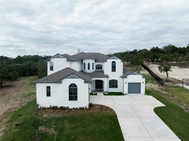 french country inspired facade featuring a front yard and a garage