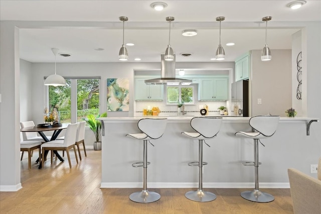 kitchen with backsplash, stainless steel fridge, kitchen peninsula, and a breakfast bar area