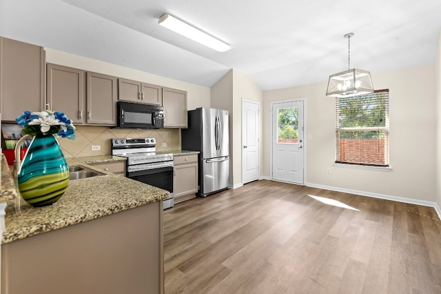 kitchen with decorative light fixtures, wood-type flooring, stainless steel appliances, and vaulted ceiling