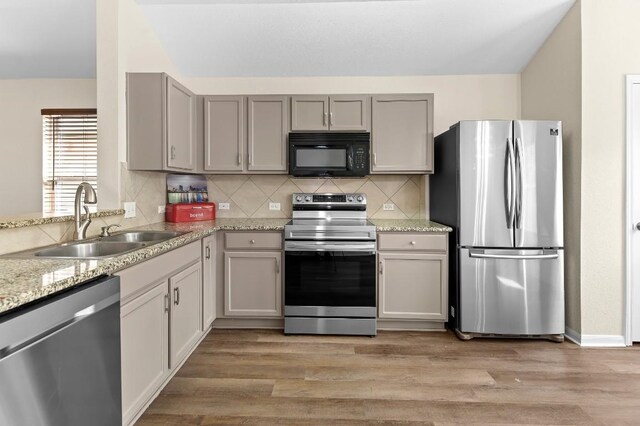 kitchen with gray cabinetry, sink, stainless steel appliances, and light hardwood / wood-style flooring