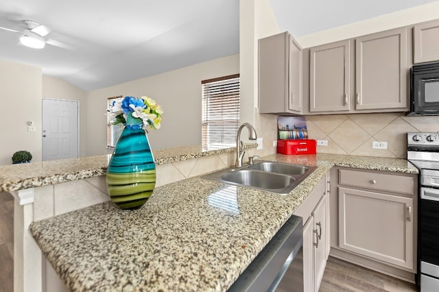 kitchen featuring kitchen peninsula, light wood-type flooring, stainless steel appliances, vaulted ceiling, and sink