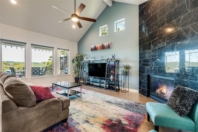 living room with beamed ceiling, high vaulted ceiling, a ceiling fan, wood finished floors, and a tile fireplace