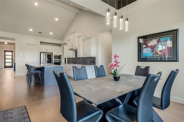 dining room with light wood finished floors, high vaulted ceiling, recessed lighting, baseboards, and visible vents