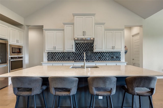 kitchen with white cabinets, tasteful backsplash, stainless steel appliances, and a kitchen island with sink