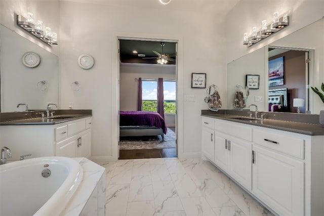 ensuite bathroom featuring a ceiling fan, two vanities, a sink, and marble finish floor
