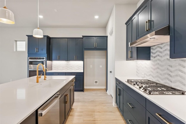 kitchen with decorative backsplash, appliances with stainless steel finishes, sink, decorative light fixtures, and light hardwood / wood-style floors