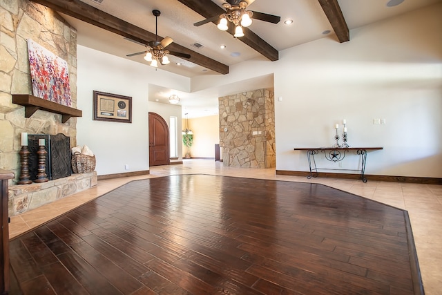 unfurnished living room with a fireplace, light wood-type flooring, beamed ceiling, and ceiling fan