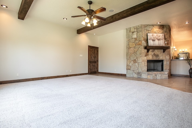 unfurnished living room with a textured ceiling, vaulted ceiling with beams, ceiling fan, and a stone fireplace