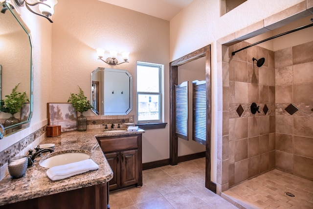 bathroom with tile patterned flooring, a tile shower, and vanity