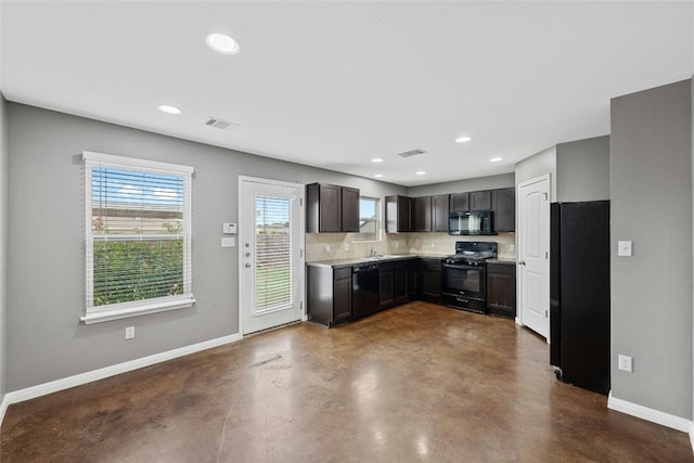 kitchen with concrete flooring, dark brown cabinets, black appliances, backsplash, and sink