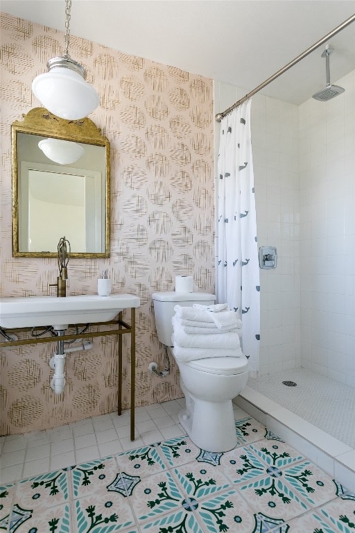 bathroom featuring toilet, curtained shower, sink, and tile patterned floors