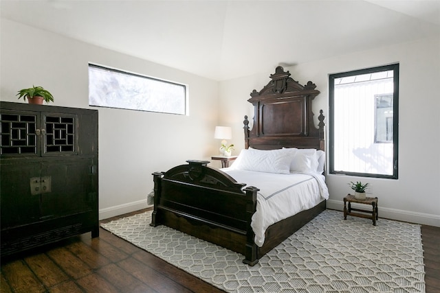 bedroom with dark wood-type flooring, vaulted ceiling, and multiple windows