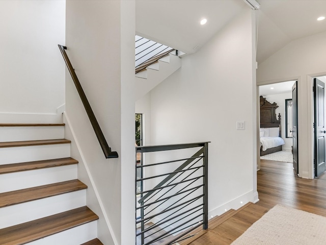 staircase featuring vaulted ceiling and wood-type flooring