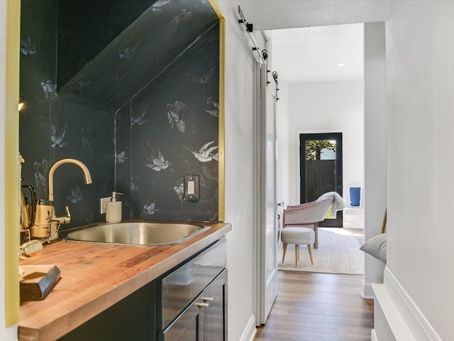 interior space with a textured ceiling, butcher block counters, sink, dark wood-type flooring, and a barn door