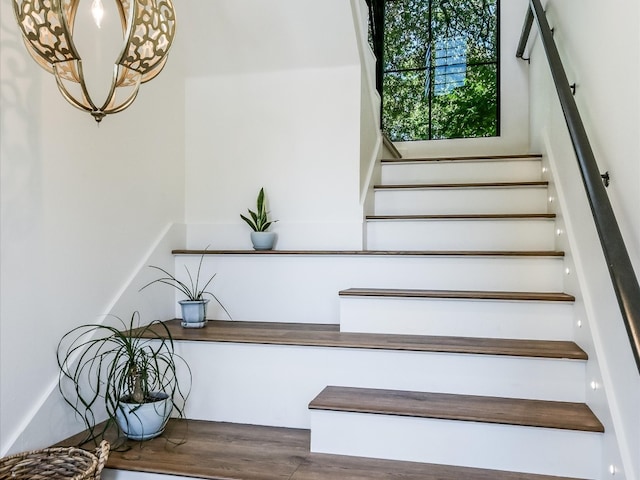 stairs featuring a notable chandelier and hardwood / wood-style flooring