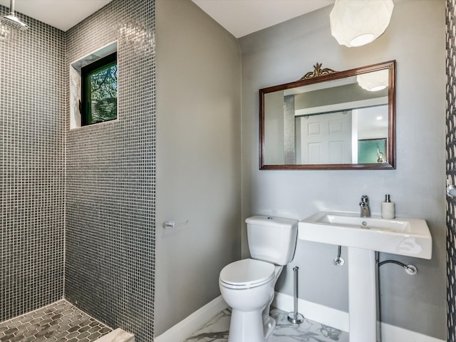 bathroom featuring tiled shower, toilet, and sink