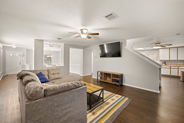 living room with ceiling fan, dark hardwood / wood-style flooring, and a textured ceiling