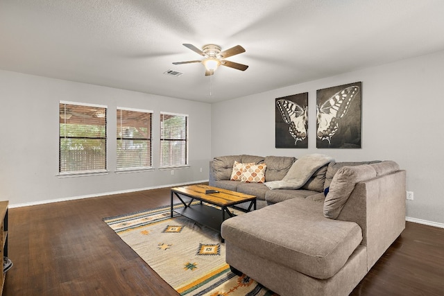 living room featuring dark wood-type flooring, a textured ceiling, and ceiling fan