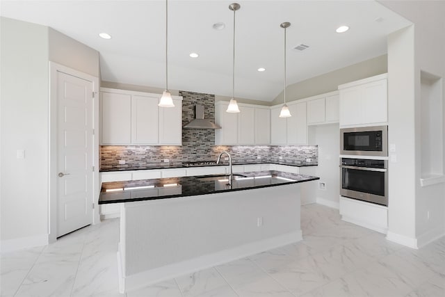 kitchen featuring oven, white cabinetry, sink, wall chimney range hood, and a center island with sink