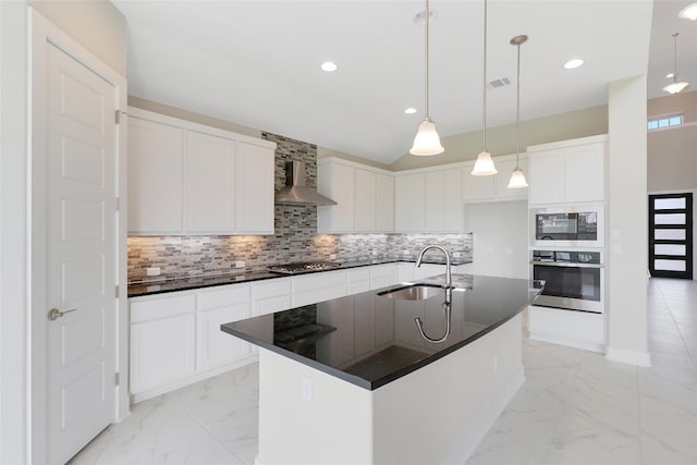 kitchen with white cabinetry, an island with sink, sink, wall chimney exhaust hood, and appliances with stainless steel finishes