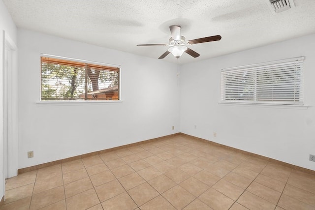 unfurnished room with ceiling fan, light tile patterned floors, and a textured ceiling