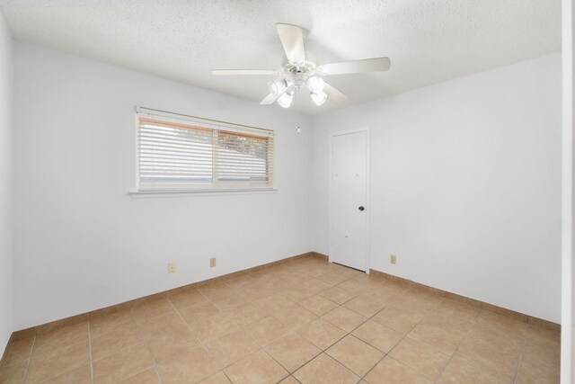 tiled empty room featuring ceiling fan and a textured ceiling