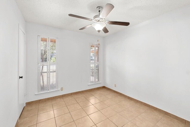 unfurnished room featuring ceiling fan, light tile patterned floors, and a textured ceiling