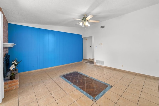 unfurnished living room featuring light tile patterned floors, wood walls, a brick fireplace, ceiling fan, and vaulted ceiling