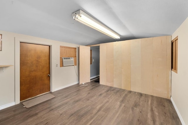 spare room with vaulted ceiling, dark hardwood / wood-style floors, and a wall mounted air conditioner