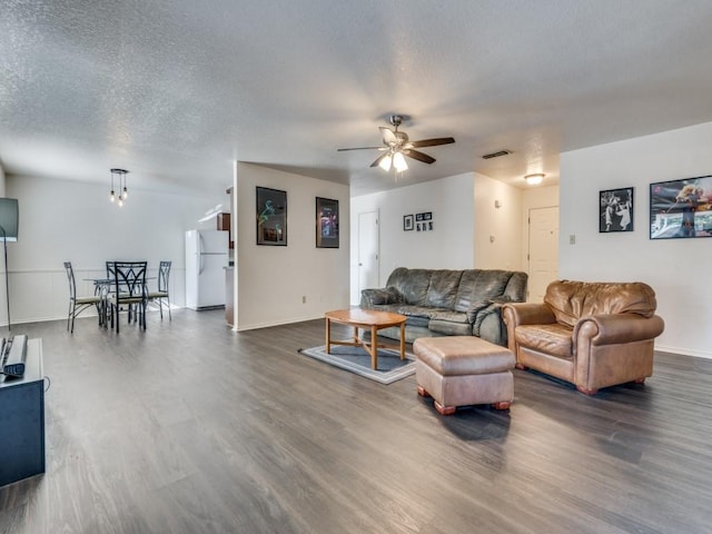 living room with baseboards, visible vents, dark wood finished floors, ceiling fan, and a textured ceiling