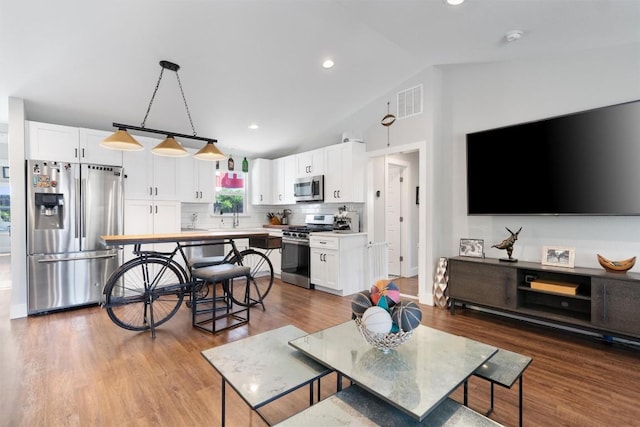 living room featuring recessed lighting, visible vents, lofted ceiling, and wood finished floors