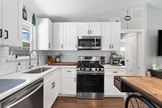 kitchen featuring lofted ceiling, dark hardwood / wood-style floors, sink, white cabinets, and appliances with stainless steel finishes