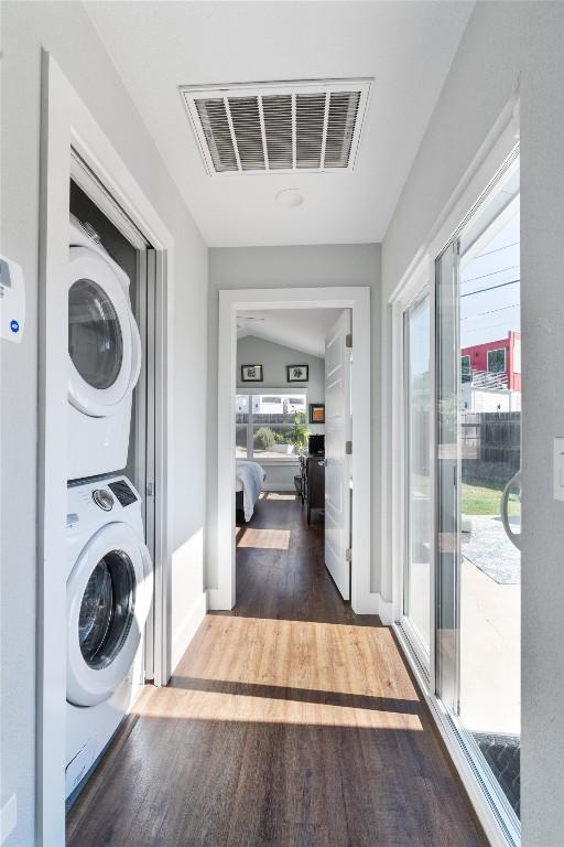 clothes washing area featuring hardwood / wood-style floors and stacked washer / drying machine